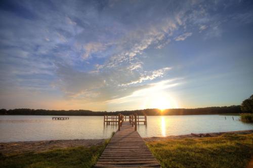 a wooden bridge over a body of water with the sunset at Aparthotel Seepanorama in Mirow