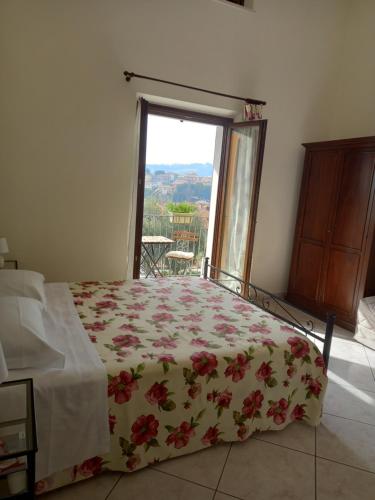 1 dormitorio con 1 cama con colcha de flores y ventana en Arra Camere Sirolo - Rooms & Suite, en Sirolo