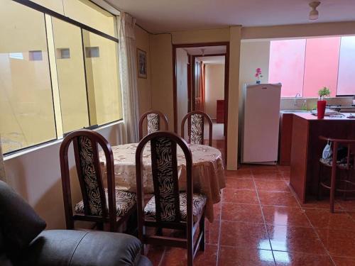 comedor con mesa, sillas y nevera en Departamento Independiente en Tacna, en Tacna