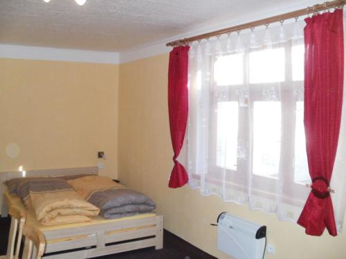 1 dormitorio con 1 cama con cortinas rojas y ventana en Rekreační dům Slavonice, en Slavonice