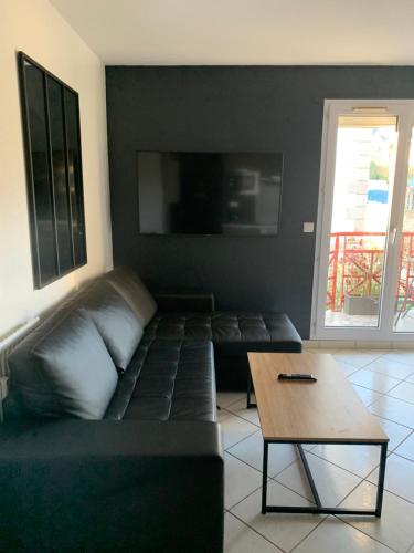 ein Wohnzimmer mit einem schwarzen Sofa und einem Tisch in der Unterkunft Top appartement 2 pièces in La Richardais