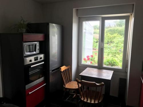 a kitchen with a table and a microwave and a window at Maison avec jardin in Crozon
