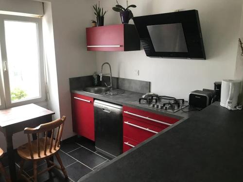 a kitchen with red cabinets and a sink and a stove at Maison avec jardin in Crozon