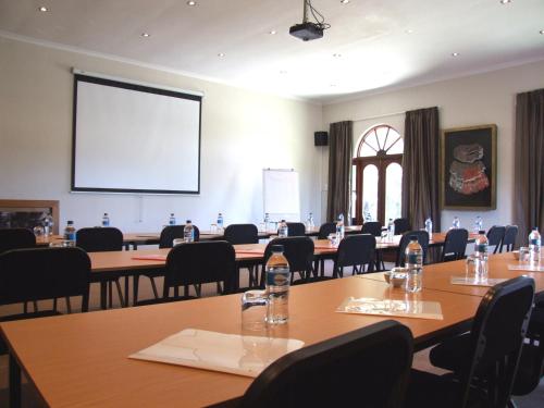 a conference room with tables and chairs and a projection screen at Cu Guest House in Phalaborwa