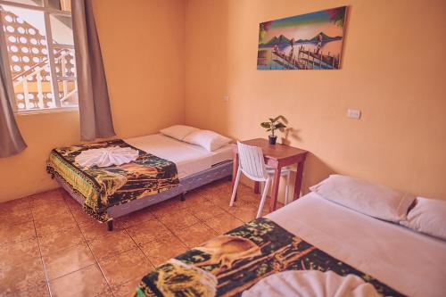 Zimmer mit 2 Betten und einem Tisch mit einem Stuhl in der Unterkunft Amigos in San Pedro La Laguna