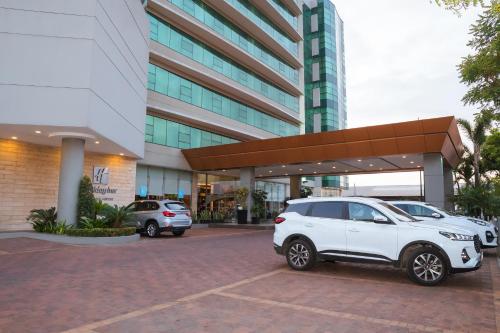 two cars parked in a parking lot in front of a building at Holiday Inn Guayaquil Airport by IHG in Guayaquil