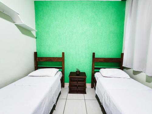 two beds in a room with green walls at Trem Bão de Ficar Hostel in Belo Horizonte
