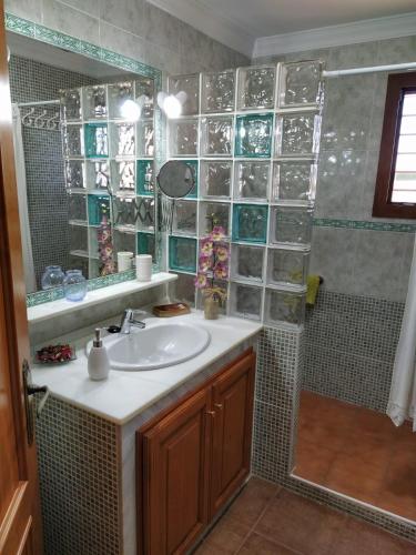 a bathroom with a sink and a shower with glass shelves at Villa Atlaymar in Barbate