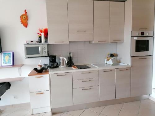 una cocina blanca con armarios y electrodomésticos blancos en Appartement Résidence Les Eucalyptus, en LʼÎle-Rousse