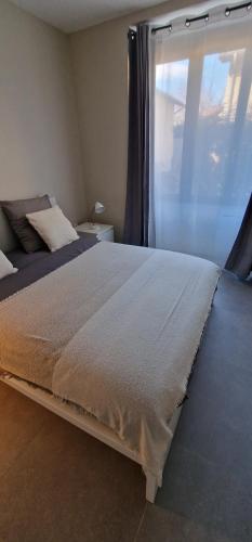 - une chambre avec un grand lit et une fenêtre dans l'établissement Beau Appartement T2, à Saint-Georges-dʼEspéranche