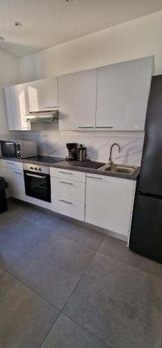 - une cuisine avec des placards blancs et un évier dans l'établissement Beau Appartement T2, à Saint-Georges-dʼEspéranche