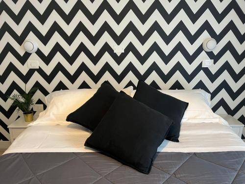 a bed with black pillows in front of a chevron wall at Appartamenti Mar y Sol in Gabicce Mare