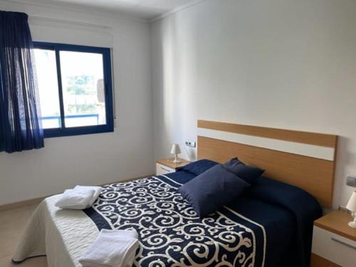 アリカンテにあるApartamento Alicante Beachのベッドルーム1室(青と白のシーツが敷かれたベッド1台、窓付)