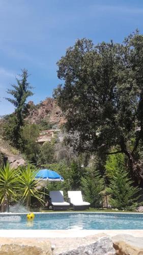 une piscine avec deux chaises et un parasol dans l'établissement 2 pièces climatisé à 200m des plages, à Théoule-sur-Mer