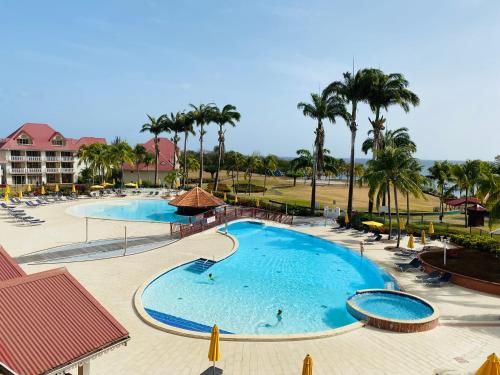 - une vue sur la piscine d'un complexe avec des palmiers dans l'établissement Curaçao 13 studio vue mer proche plage dans Complexe type Village Vacances, à Sainte-Luce