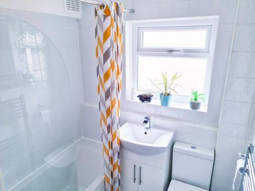 a bathroom with a toilet and a sink and a window at The Navarone Blue Orchid Flat in London