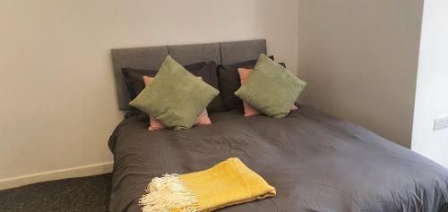 uma cama com quatro almofadas e uma cabeceira cinzenta em Leicester Central Apartments em Leicester