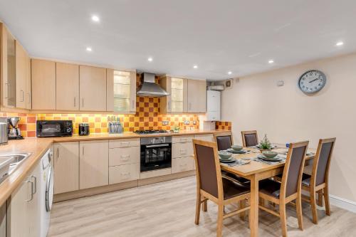 a kitchen with a table and chairs and a clock on the wall at Stylish Apartment Near Norwich Cathedral & Castle in Norwich