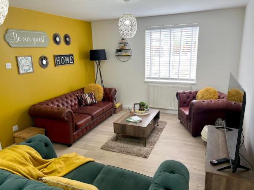a living room with brown leather couches and a table at Stylish 3 bedroom seaside escape - newly renovated in Paignton