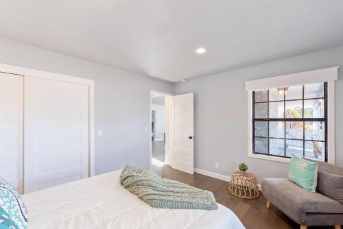 a white bedroom with a bed and a chair at 3849 La Vista Portola home in Del Rey Oaks