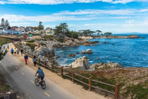 a man riding a bike down a road next to the ocean at 3849 La Vista Portola home in Del Rey Oaks