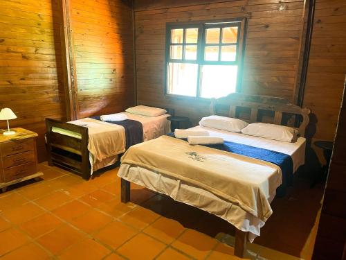 a room with two beds and a tv in it at Pousada Recanto das Hortênsias in Cunha