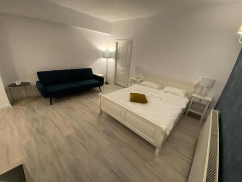 a bedroom with a white bed and a blue couch at TEN APARTAMENT in Eforie Nord