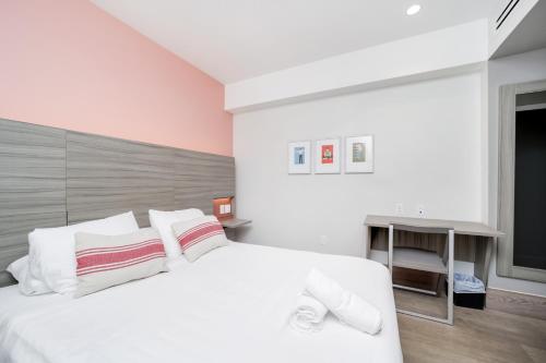 a white bedroom with a large white bed and a desk at The Julia Hotel in Miami Beach