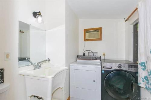 a white laundry room with a washing machine and a sink at Charming Country Cottage just a few steps from the beach! in Waianae