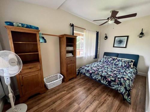 1 dormitorio con 1 cama y ventilador de techo en Charming Country Cottage on quiet street just a few steps from the beach!, en Waianae