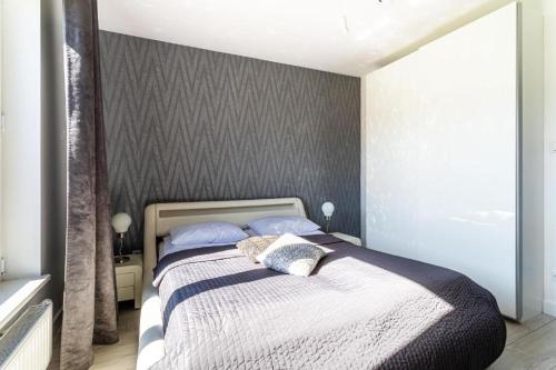 a bedroom with a bed with a gray wall at Apartament Old Town Tartaczna 43 in Gdańsk