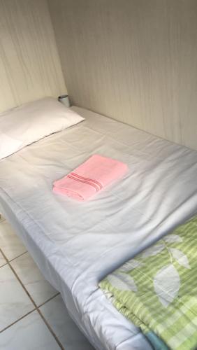 Una cama blanca con una toalla rosa. en Hostel Gomes, en São Paulo