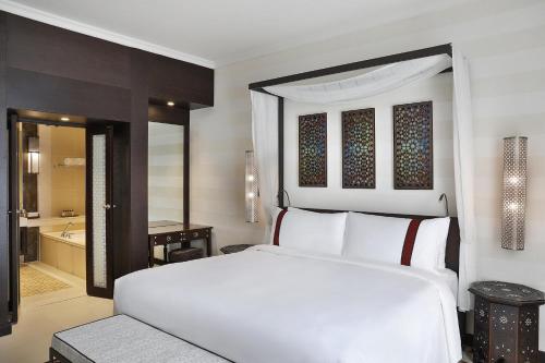 a bedroom with a white bed and a bathroom at Al Manara, a Luxury Collection Hotel, Aqaba in Aqaba