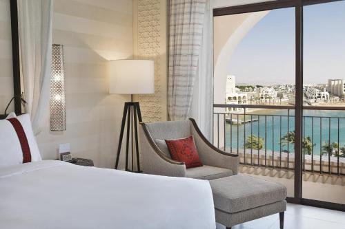 a bedroom with a bed and a chair and a window at Al Manara, a Luxury Collection Hotel, Aqaba in Aqaba