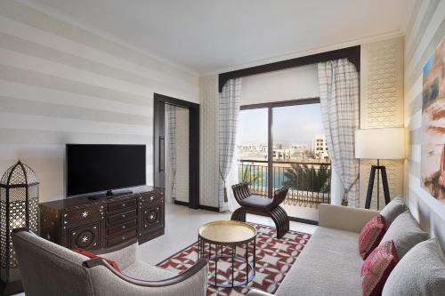 a living room with a television and a couch and a table at Al Manara, a Luxury Collection Hotel, Aqaba in Aqaba