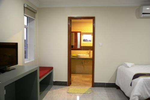 a bedroom with a bed and a television and a bathroom at Neakru Guesthouse and Restaurant in Kampot