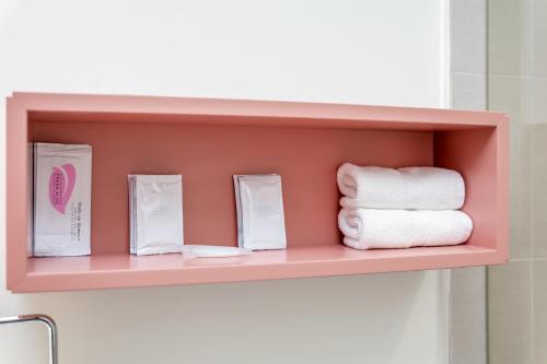a pink shelf with towels on it in a bathroom at The Julia Hotel in Miami Beach