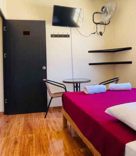 a room with a bed and a table and a tv at Hospedaje La Posada del Chino in Los Órganos