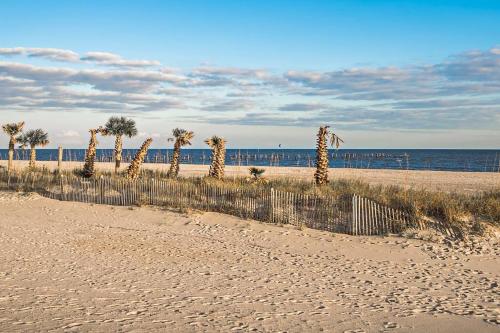 a sandy beach with palm trees and the ocean at Relaxing 5-Bedroom Villa with Outdoor Oasis in Bay Saint Louis