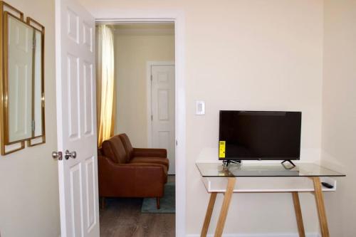 een woonkamer met een televisie op een tafel en een stoel bij LUXE Private & Modern Close to New York City in New Rochelle