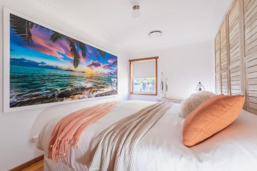 a white bedroom with a large painting on the wall at Cool Change Accommodation And Venue Hire in Nelson Bay