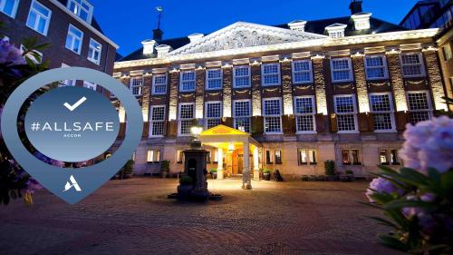 een groot gebouw met een bord ervoor bij Canal House Suites at Sofitel Legend The Grand Amsterdam in Amsterdam