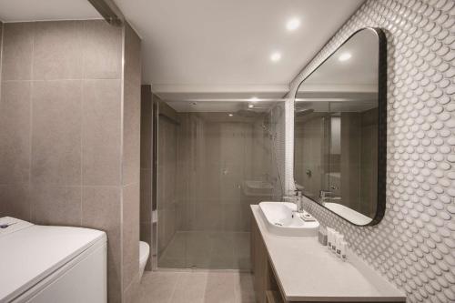 雪梨的住宿－悉尼庫吉海阿迪納公寓式酒店，一间带水槽、淋浴和镜子的浴室