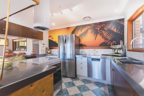 a kitchen with stainless steel appliances and a palm tree mural at Cool Change Accommodation And Venue Hire in Nelson Bay