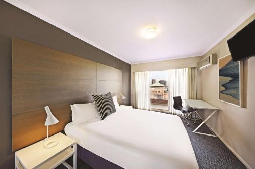 a hotel room with a large bed and a window at Adina Apartment Hotel Sydney Surry Hills in Sydney