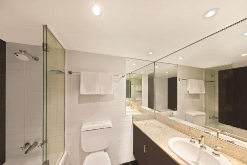 La salle de bains est pourvue de toilettes, d'un lavabo et d'un miroir. dans l'établissement Adina Apartment Hotel Sydney Surry Hills, à Sydney