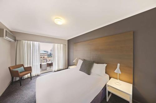 Habitación de hotel con cama y silla en Adina Apartment Hotel Sydney Surry Hills en Sídney