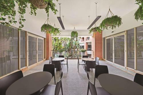 a row of tables and chairs in a room with windows at Adina Apartment Hotel Sydney Surry Hills in Sydney