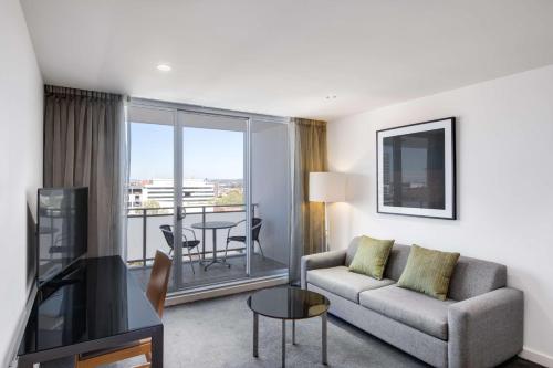 a living room with a couch and a room with a balcony at Adina Apartment Hotel Wollongong in Wollongong