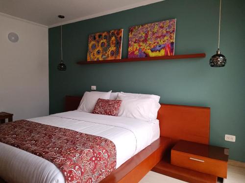 a bedroom with a bed and some paintings on the wall at Hotel Boutique Confort Suites in Popayan